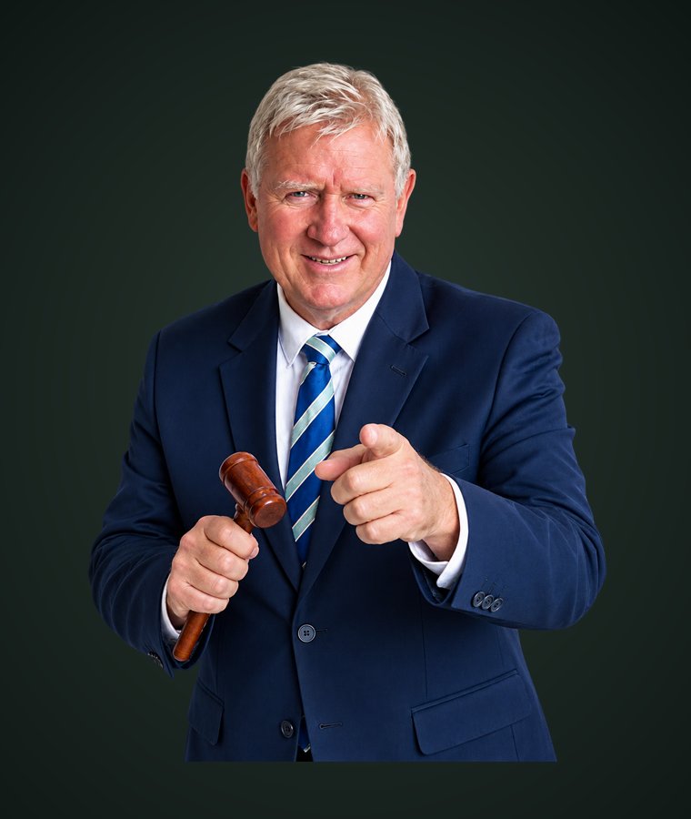 Andrew Miller in a navy suit, holding an auctioneer's gavel